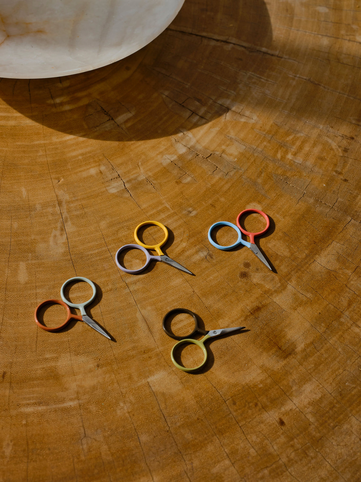 Four DEGEN Two Tone Circle Mini Scissors on a wooden surface, including Koi + Mist and Moss + Sprig | Koi + Mist, Moss + Sprig