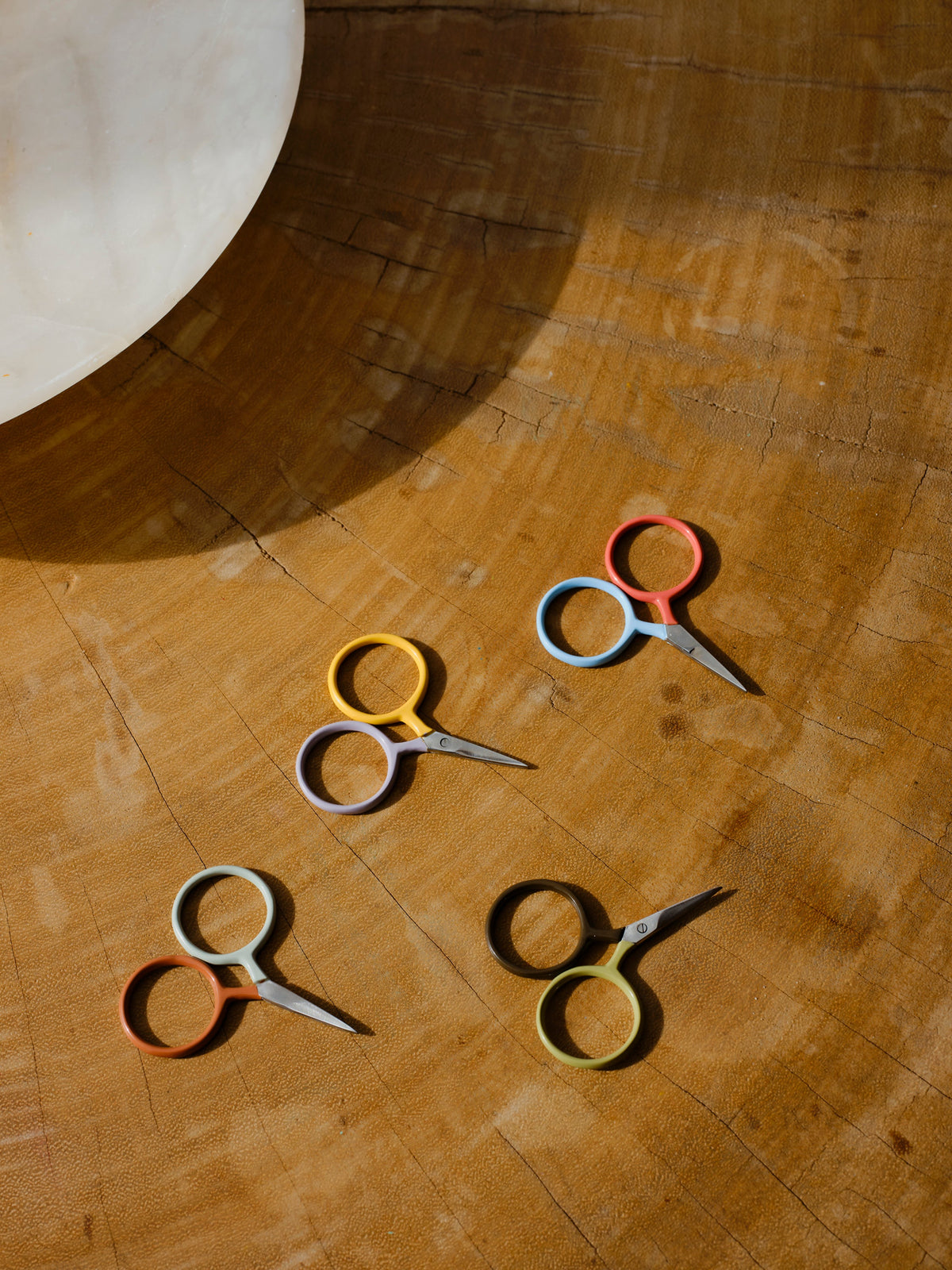 Four DEGEN Two Tone Circle Mini Scissors in an alternate arrangement on wood, including Koi + Mist and Moss + Sprig | Koi + Mist, Moss + Sprig