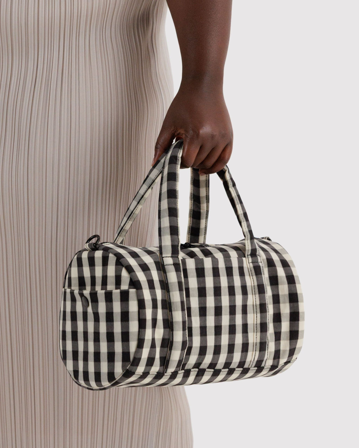 BAGGU Nylon Duffle Bag in Black and Cream Gingham, carried by the padded handles | Black and Cream Gingham