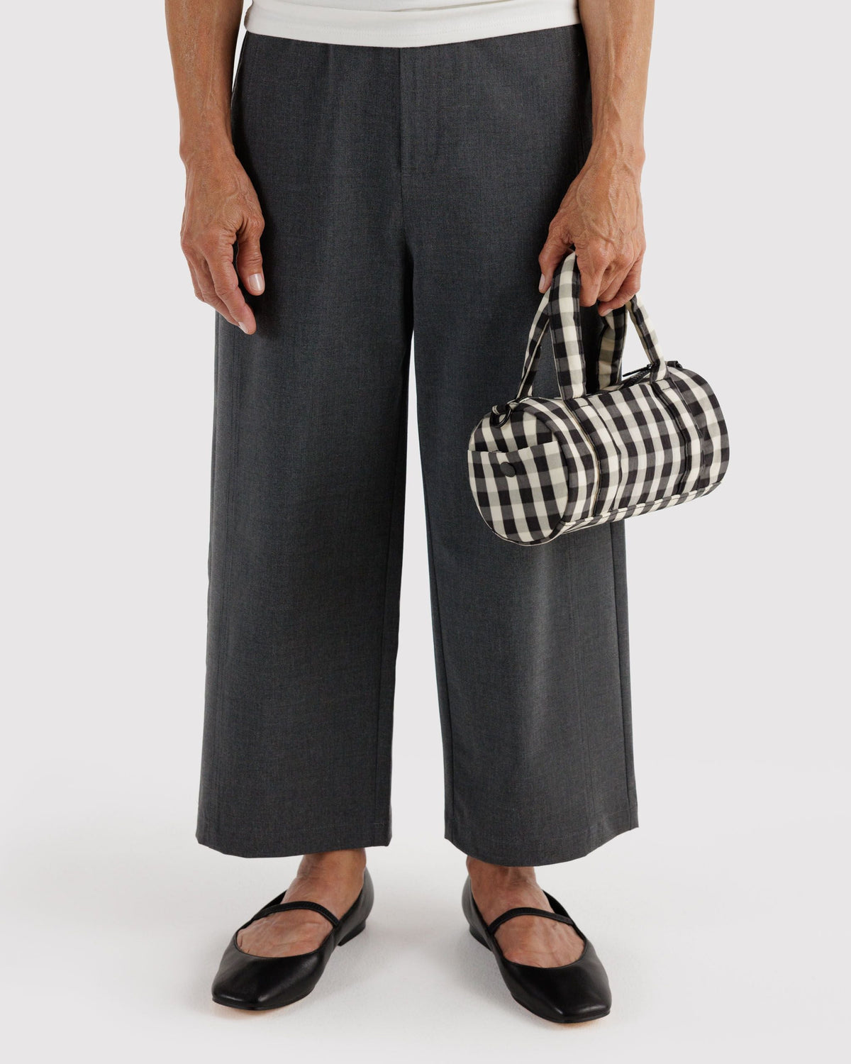 BAGGU Small Nylon Duffle Bag in Black and Cream Gingham, carried by the padded handles | Black and Cream Gingham