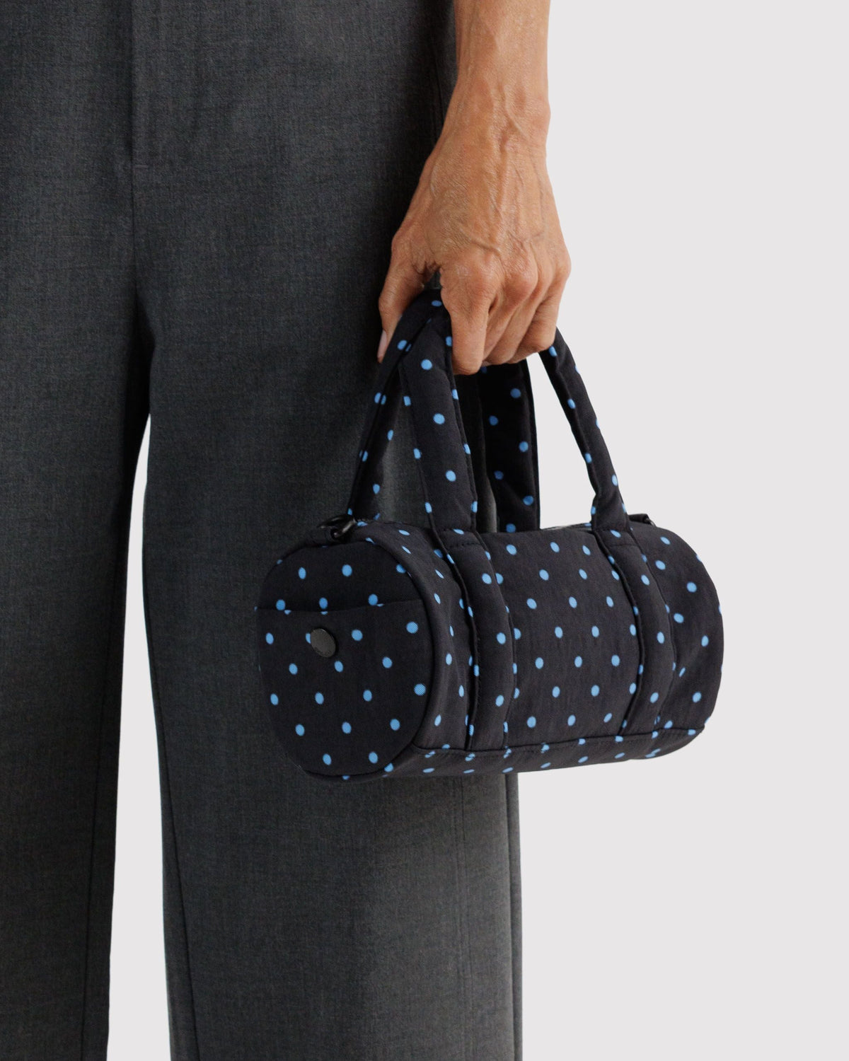 BAGGU Small Nylon Duffle Bag in Black and Sky Blue Micro Dot, carried by the padded handles | Black and Sky Blue Micro Dot