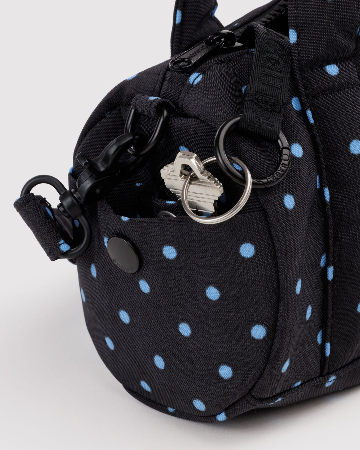 BAGGU Small Nylon Duffle Bag in Black and Sky Blue Micro Dot, side pocket and key leash detail | Black and Sky Blue Micro Dot