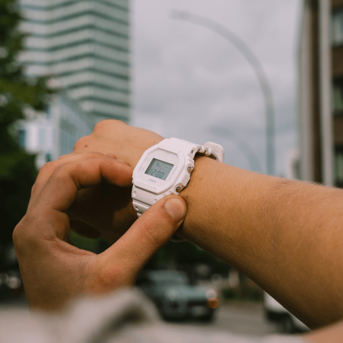 G-Shock DW5600WW-7 digital watch worn on a wrist while pressing a side button | White