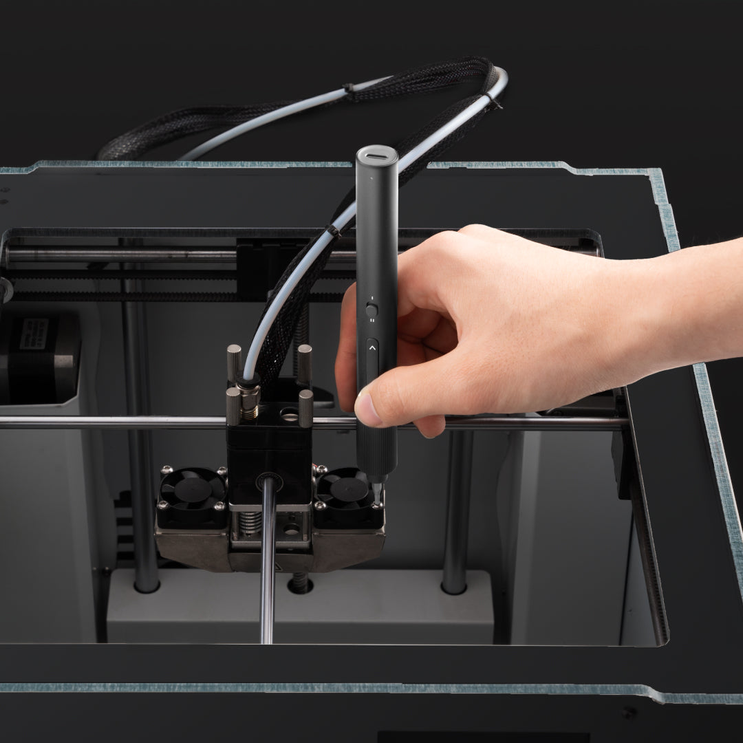Hand holding a 3D printing pen above a 3D printer
