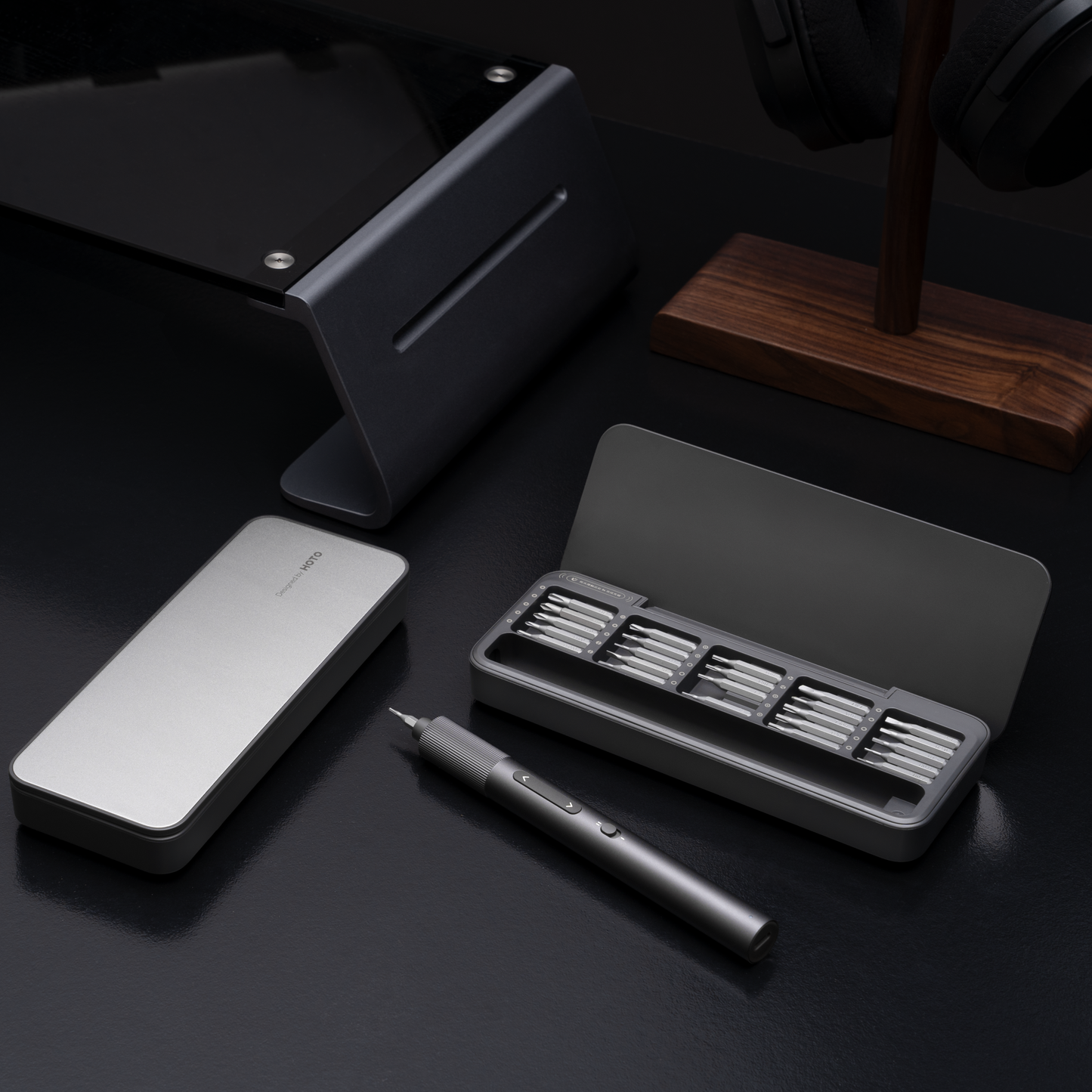Set of tools including a pen, stand, and small container on a dark surface
