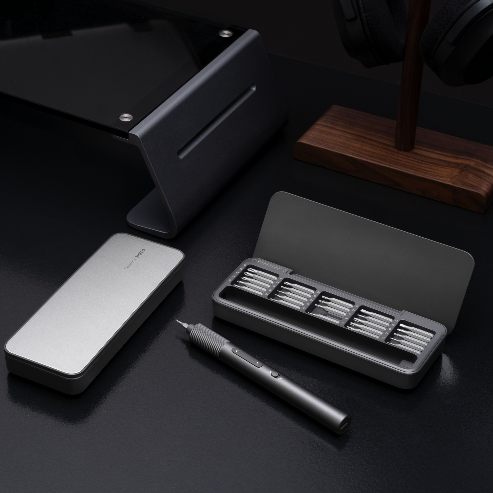 Set of tools including a pen, stand, and small container on a dark surface