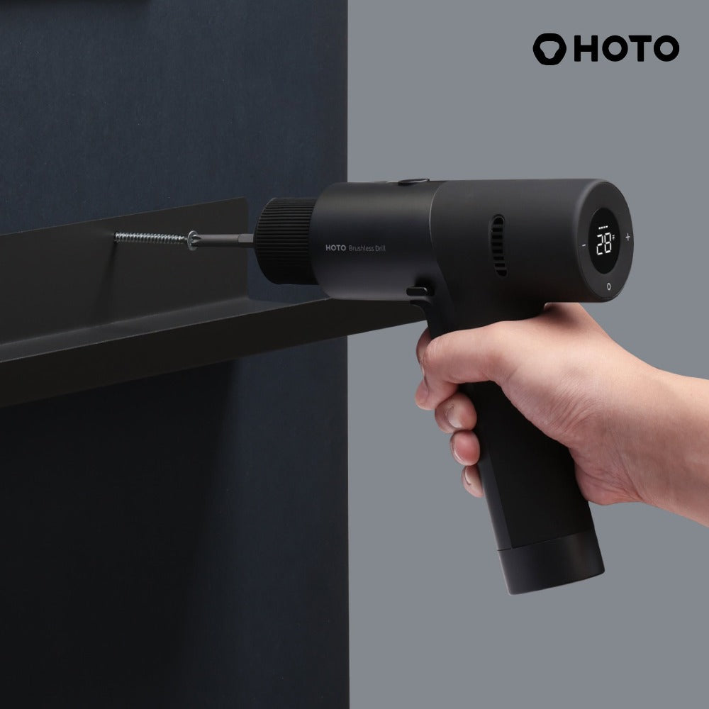 Hand holding a black HOTO screwdriver against a gray background