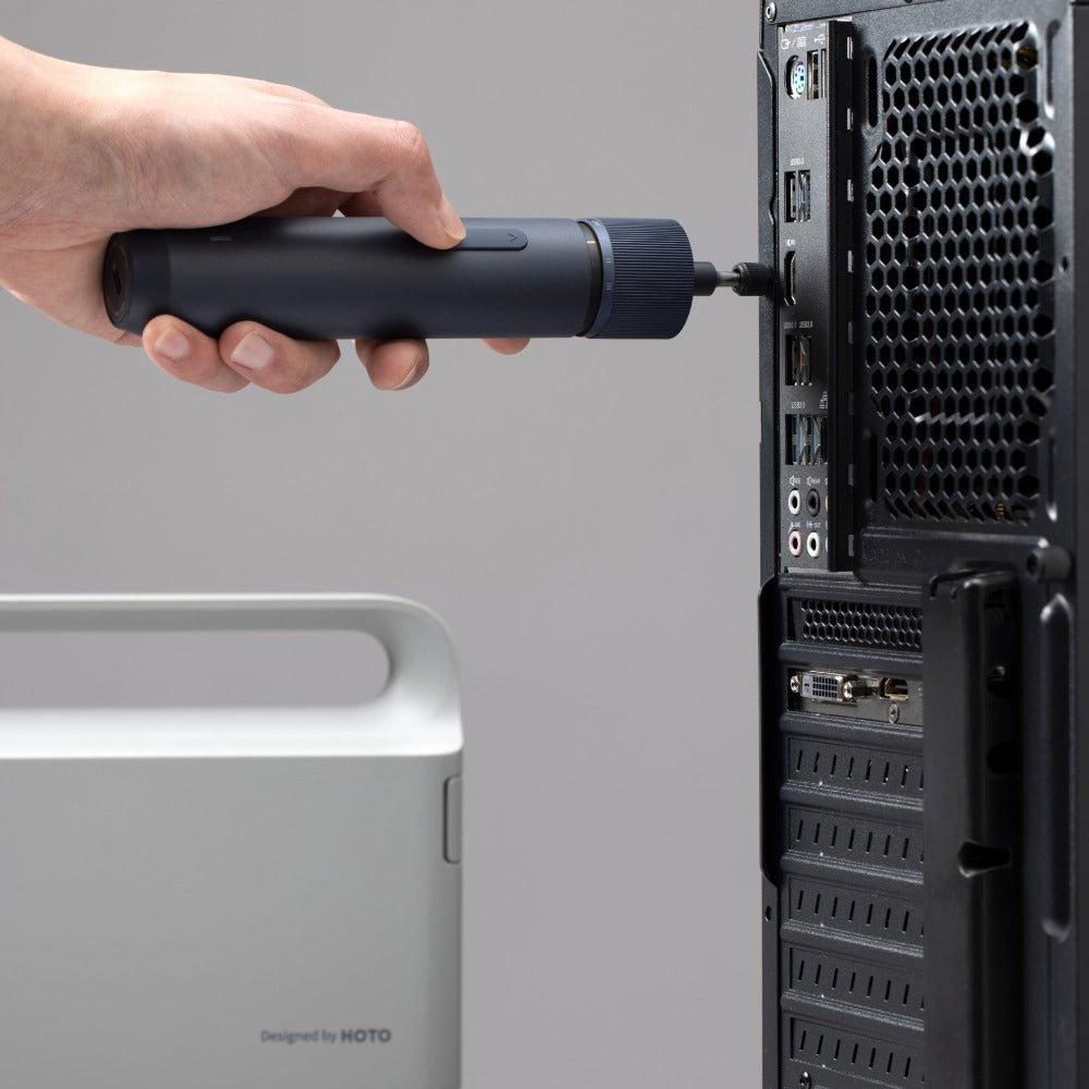 Hand using a screwdriver to work on a computer tower with a gray background