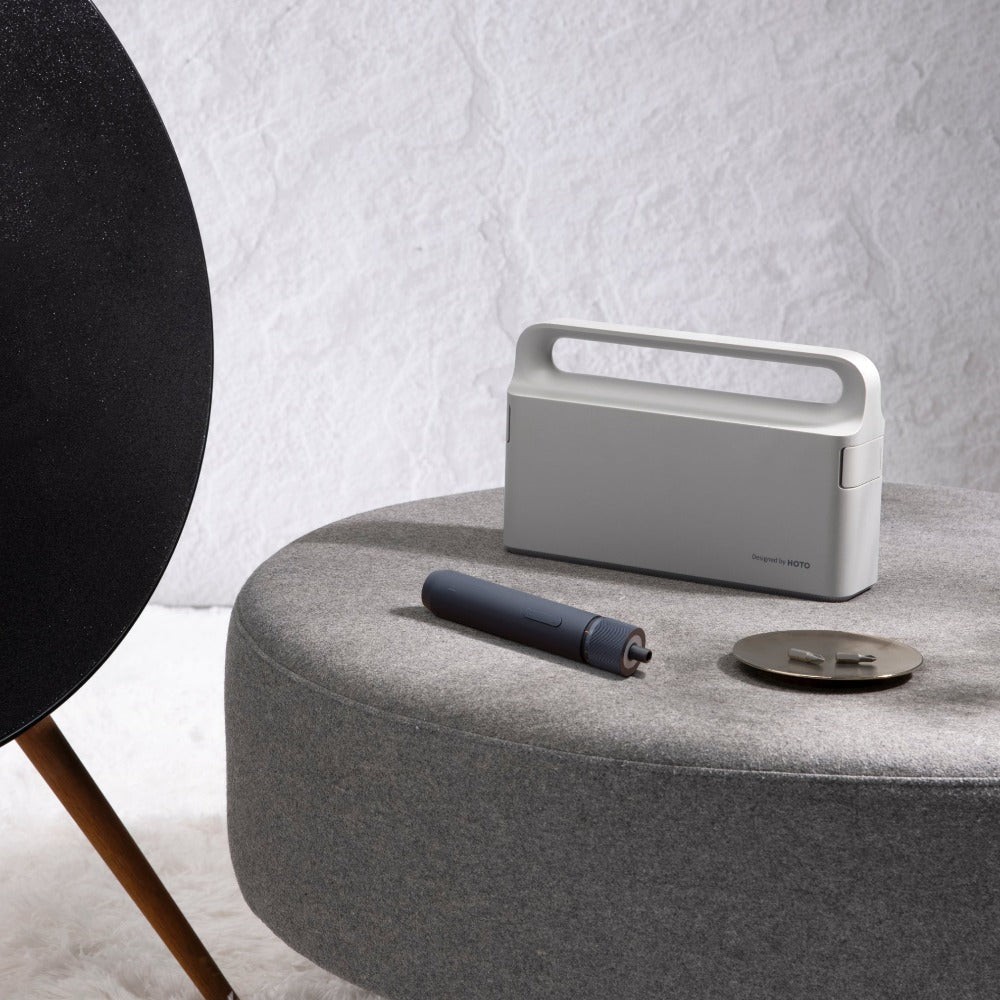 Portable power station on a round gray table with a black chair and white wall in the background. HOTO 3.6V Screwdriver Tool Set