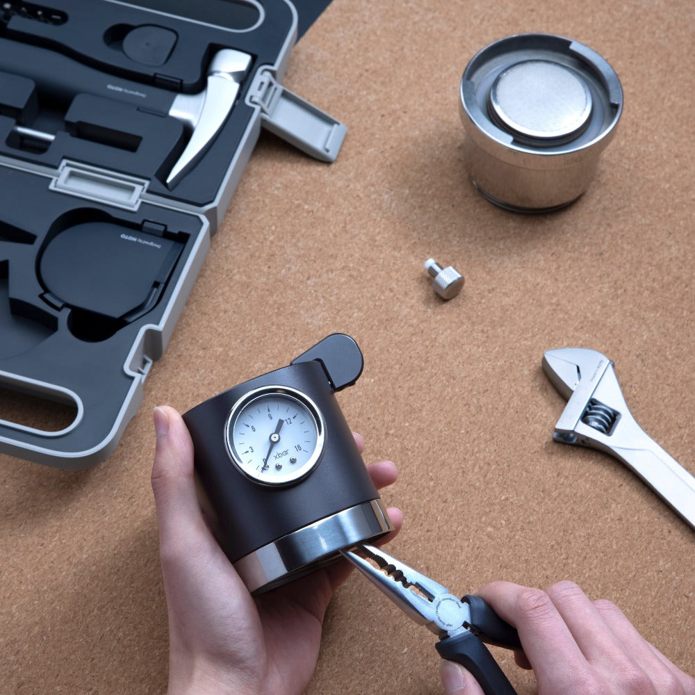 Person using a tool with a gauge on a wooden surface with tools and equipment.