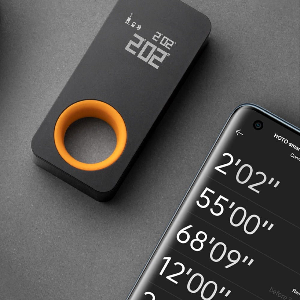 Black and orange measuring device next to a smartphone displaying measurement readings on a gray background, HOTO Laser Measure