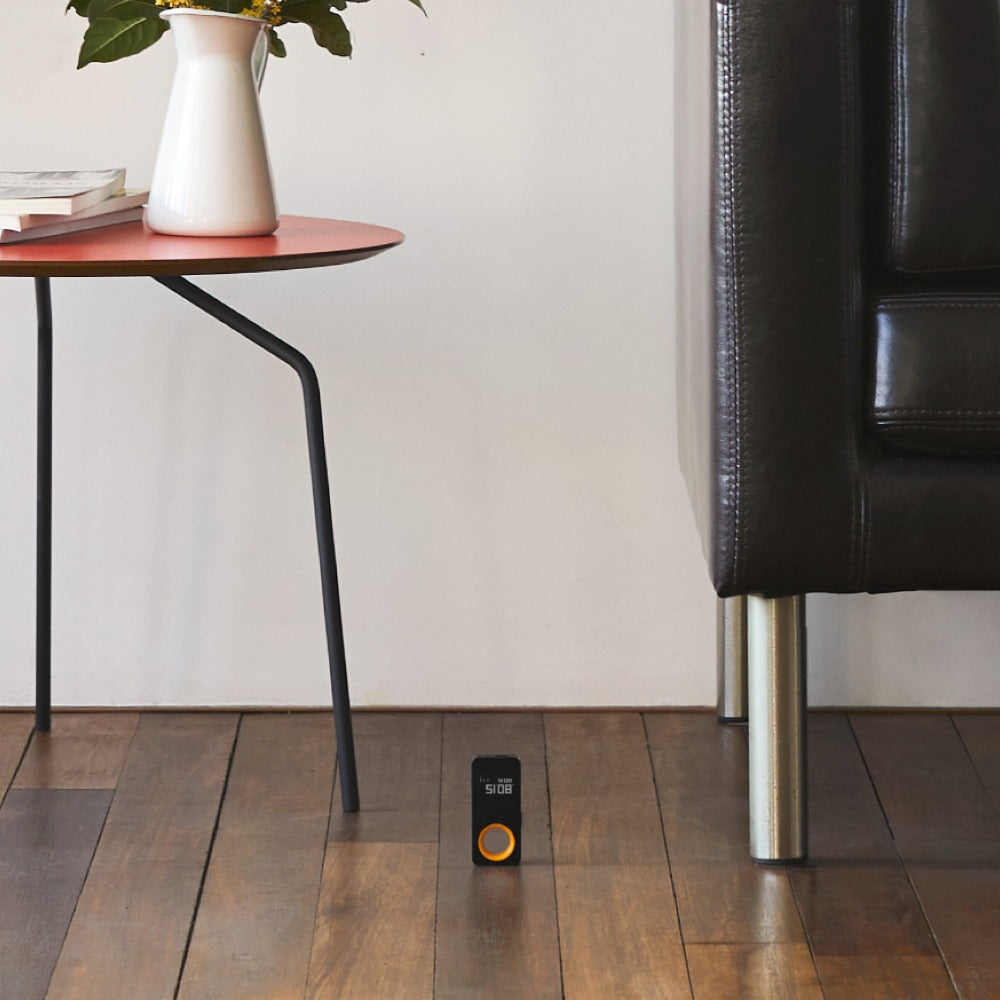 Smart home device on a wooden floor with a table and chair in the background