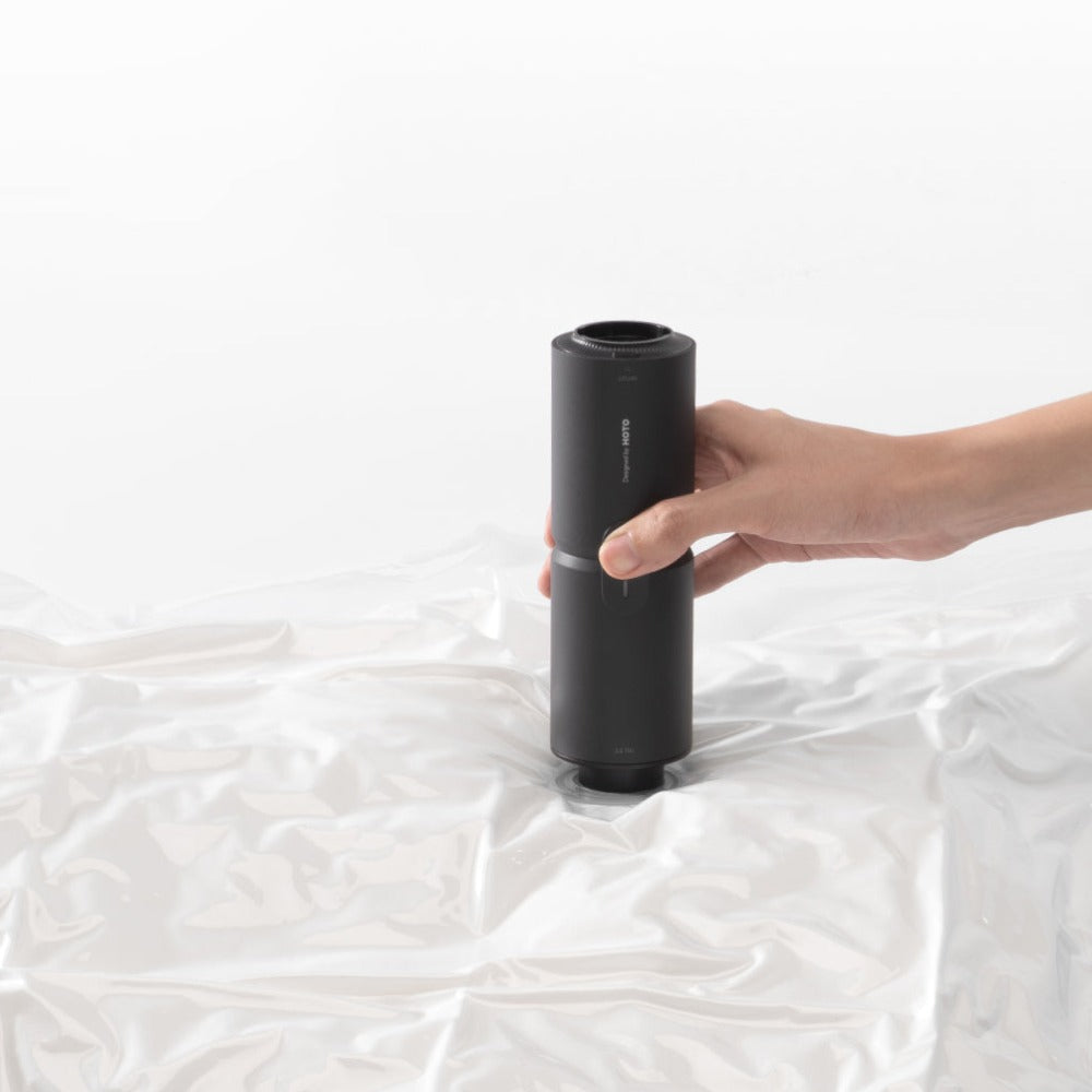 Hand using a black vacuum pump on a white mattress HOTO Compressed Air Capsule