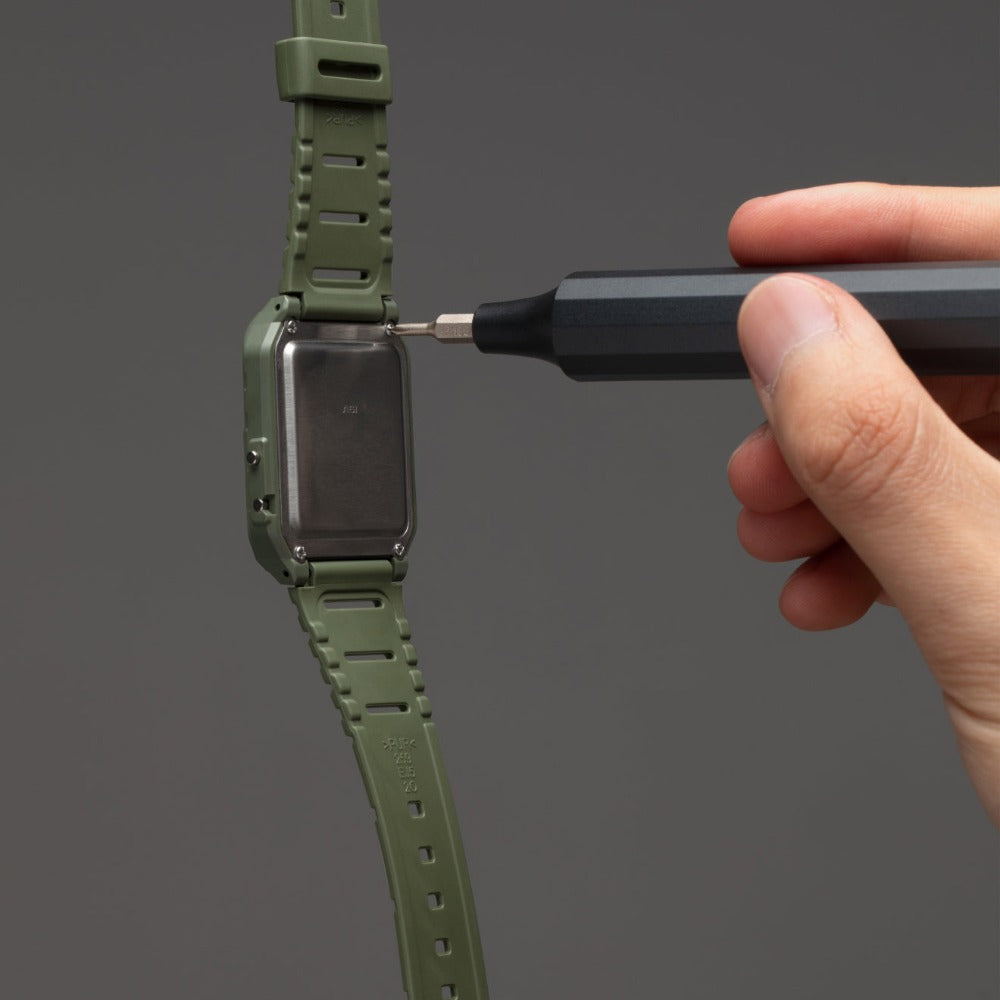 Person adjusting a green smartwatch strap with a tool on a gray background  | Charcoal Black