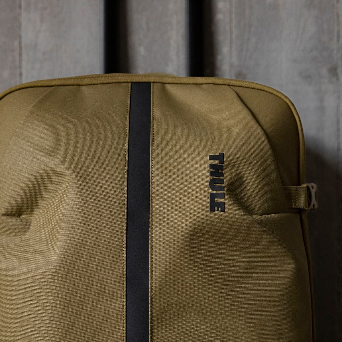 Green backpack with a black strap and 'Thule' branding on a textured gray background | Dark Slate