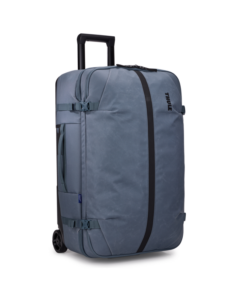 A slate blue Thule rolling suitcase with a telescoping handle extended, featuring black side straps and a vertical black zipper track on a white background. THULE Aion Wheeled Duffel Bag 70CM/28