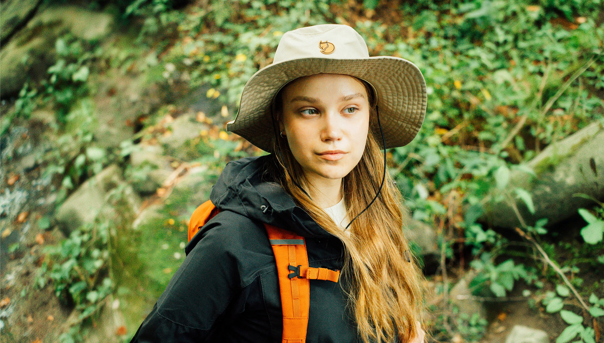 Person wearing a Fjällräven hat and an orange backpack outdoors