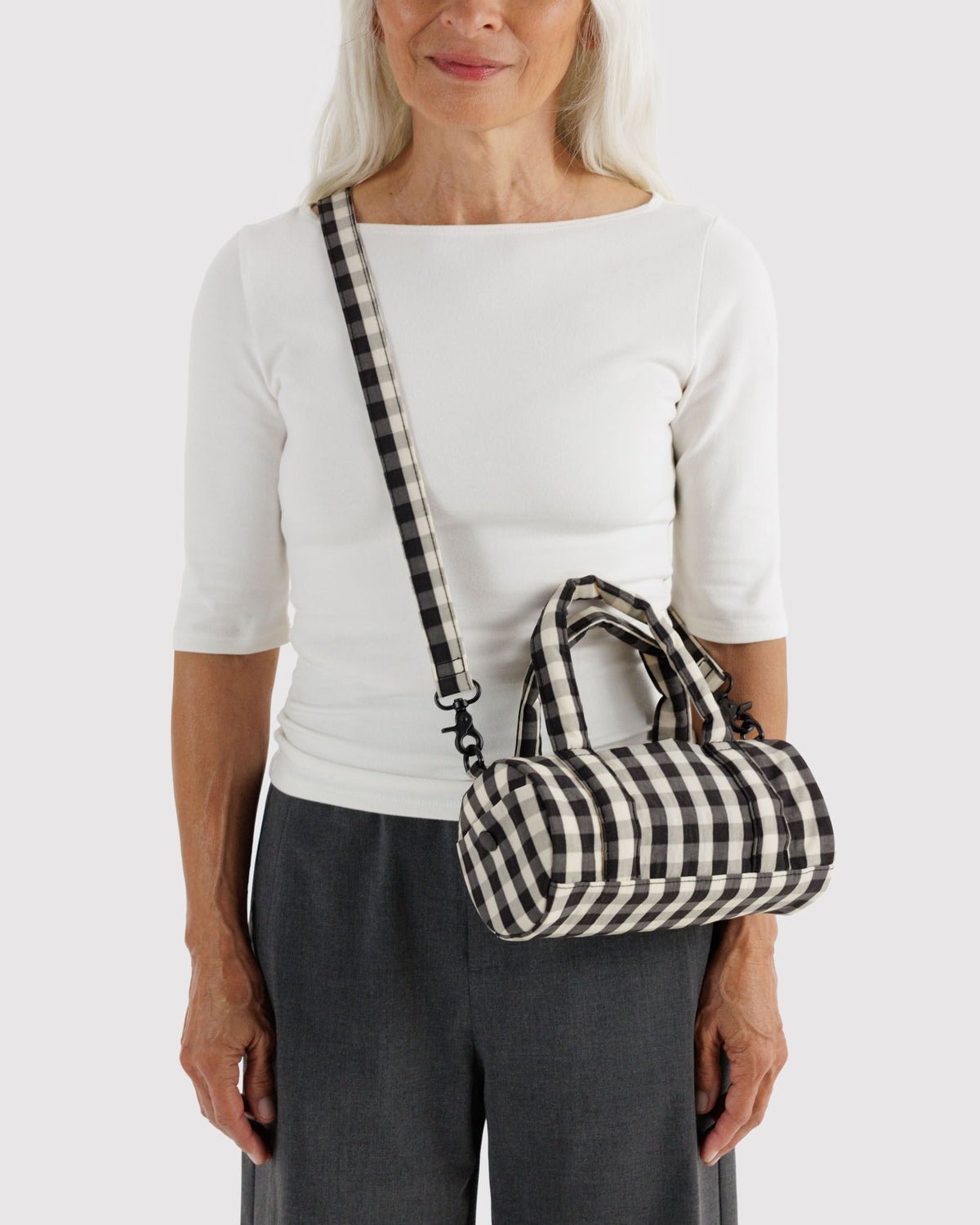 BAGGU Small Nylon Duffle Bag in Black and Cream Gingham, worn crossbody | Black and Cream Gingham