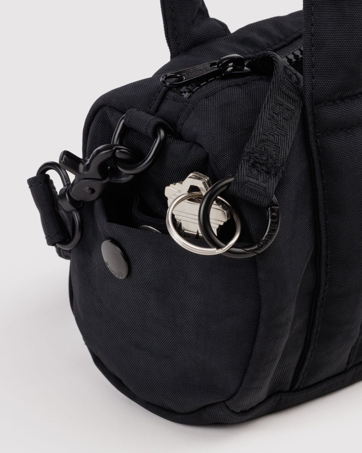 BAGGU Small Nylon Duffle Bag in Black, side pocket and key leash detail | Black