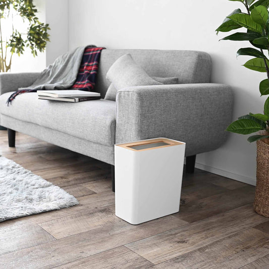 Yamazaki Home Rin Trash Can - Rectangle - Steel + Wood, Ash-lid white bin beside a gray sofa