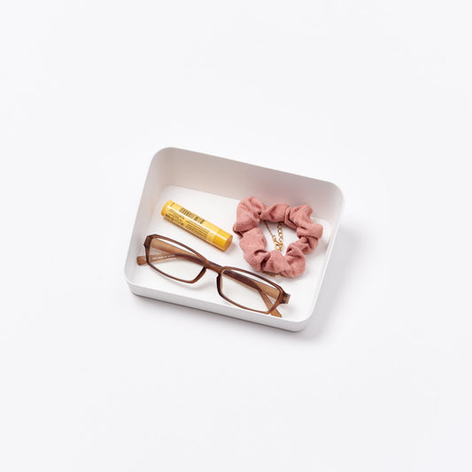 Yamazaki Tower small white angled vanity tray holding eyeglasses, a scrunchie and lip balm; accessories not included.