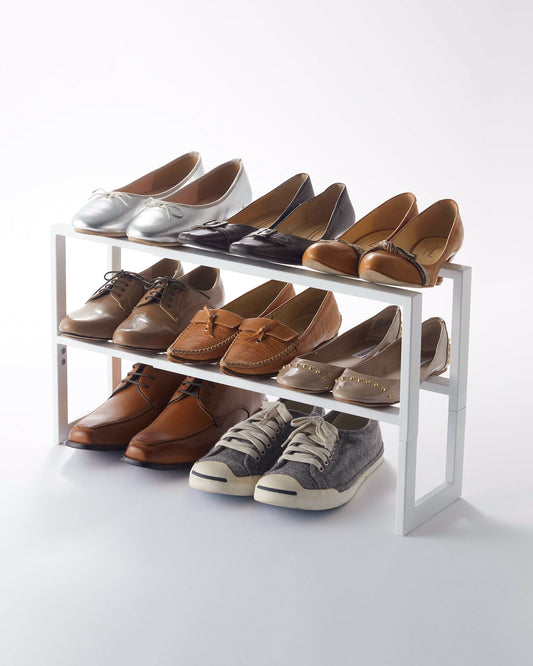 White Yamazaki Line two-tier shoe rack with separate shoes on both tiers and additional pairs on the floor beneath.