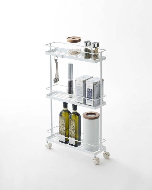 Yamazaki Home Tower Rolling Cart (26" H) - Steel, white three-tier cart holding bottles and kitchen supplies
