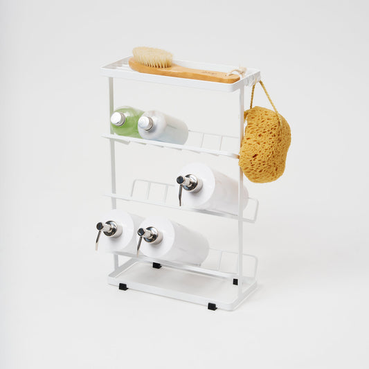 Yamazaki Tower white four-tier shower caddy with a top shelf and three angled bottle racks, styled with bath products and a hanging sponge; contents not included.