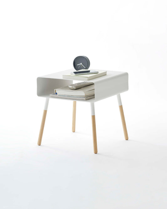 Yamazaki Plain short white storage side table with wooden legs, styled with a clock, books and remote; accessories not included.