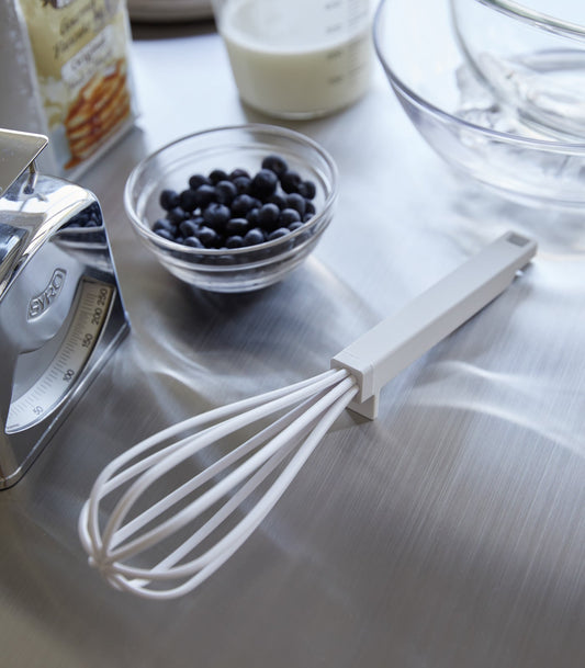 Yamazaki Home Tower Floating Whisk - Silicone and Nylon, white whisk resting beside baking ingredients